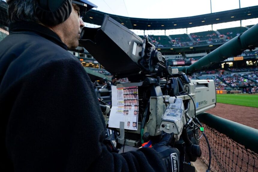 FILE - A sheet showing Boston Red Sox players photos hangs from a camera as a broadcast operator works during the first inning of a baseball game between the Baltimore Orioles and the Red Sox, Monday, April 24, 2023, in Baltimore, Md. (AP Photo/Julio Cortez, File)