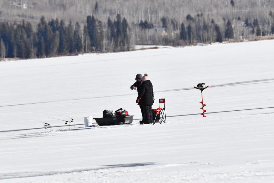 A couple fishing on about three inches of ice near the County Boat Dock on the west side of Henrys Lake.