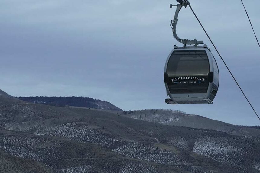 A gondola hangs in front of snow-scarce mountains Thursday, Dec. 18, 2025, in Avon, Colo. (AP Photo/Brittany Peterson)