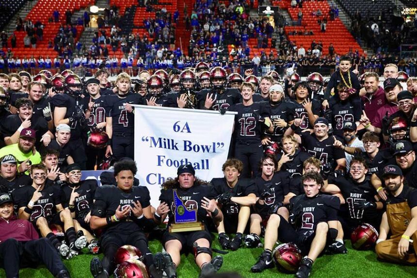 The Rigby High School Trojans pose with their newest 6A “Milk Bowl” state football championship banner, which they claimed with a 41-6 victory over Timberline, Saturday. | Kyle Riley, EastIdahoSports.com
