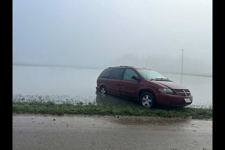 A minivan is stuck after flooding along Tualco Road near Monroe, Washington, on Dec. 13, 2025. The Northwest is seeing warm rains instead of snow in much of the region, concerning climate scientists. (Photo by Jake Goldstein-Street/Washington State Standard)