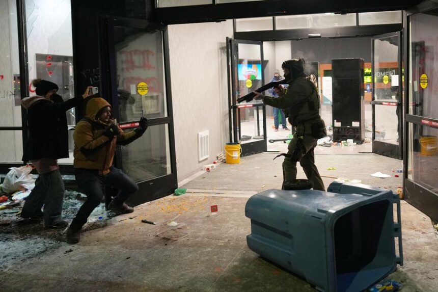 A federal agent points a weapon at a person outside a hotel during a noise demonstration protest in response to federal immigration enforcement operations in the city Sunday, Jan. 25, 2026, in Minneapolis. | Adam Gray, Associated Press