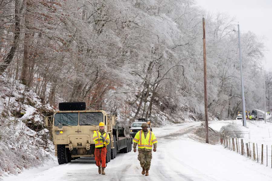 Tennessee National Guard members Taylor Osteen, left, and Antuwan Powell walk along an ice covered road as they work to remove trees Friday, Jan. 30, 2026, in Nashville, Tenn.