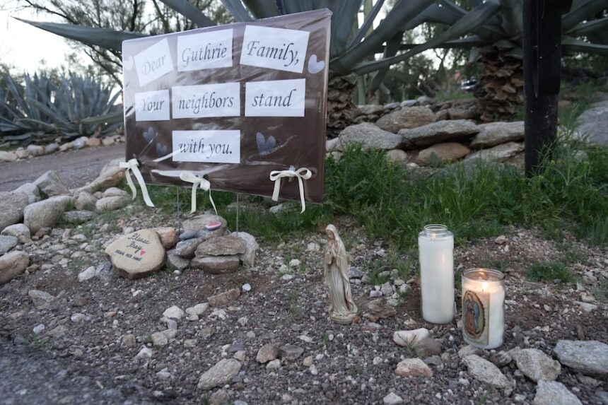 Lit candles next to a sign from neighbors supporting the Guthrie family outside of Nancy Guthrie’s house in the early morning hours of Sunday, Feb. 8, 2026 in Tucson, Ariz.