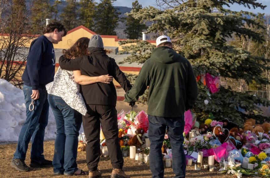 Residents hug as they place flowers at a memorial for the victims of Tuesday's mass shooting in Tumbler Ridge, British Columbia, Canada, on Thursday, Feb. 12, 2026.