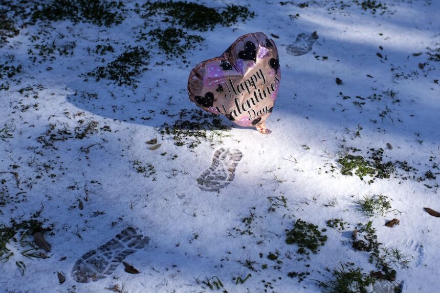 A Valentine's Day balloon floats past footprints in the snow in Houston on February 15, 2021.