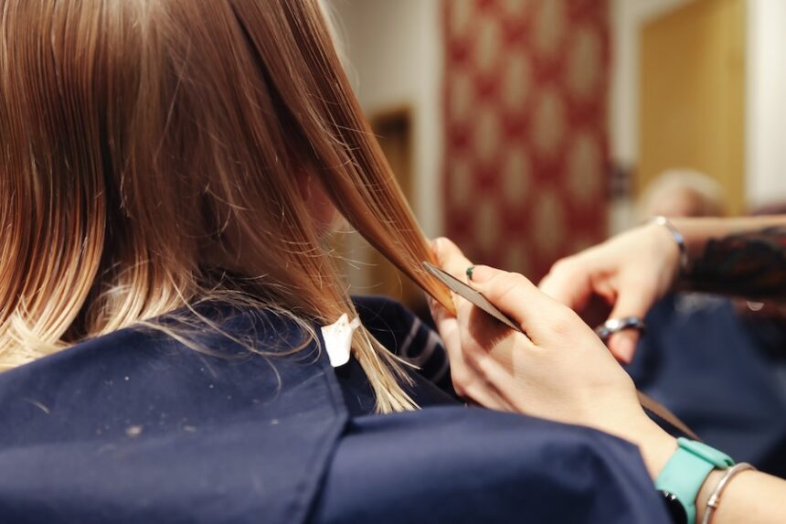 Hair salon. Close-up of little girl visits hairdresser, make fashionable hairstyle, rear view. Hands of barber cutting hair, hairdo for baby in barbershop. Hairstyles, beauty concept. Copy text space