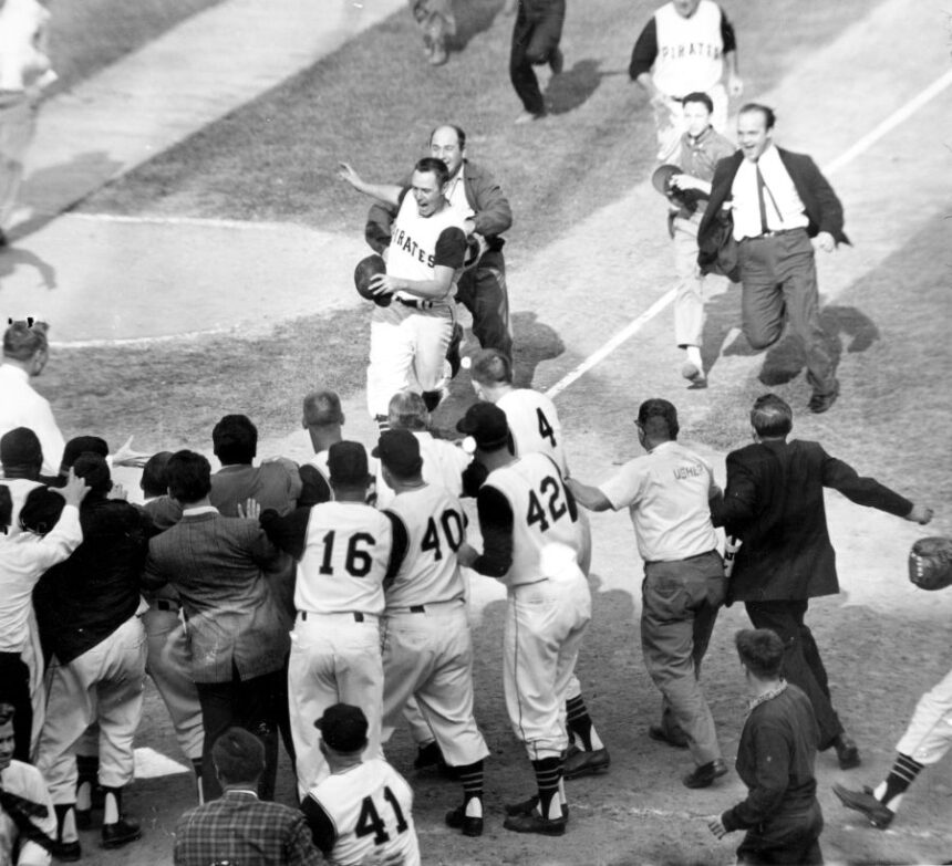 FILE - Baseball fans rush onto the field toward Pittsburgh Pirates second baseman Bill Mazeroski as he comes home after hitting a ninth inning home run to win Game 7 of baseball's World Series agains the New York Yankees in Pittsburgh, Pa., on Oct. 13, 1960. (AP Photo/Harry Harris, File)