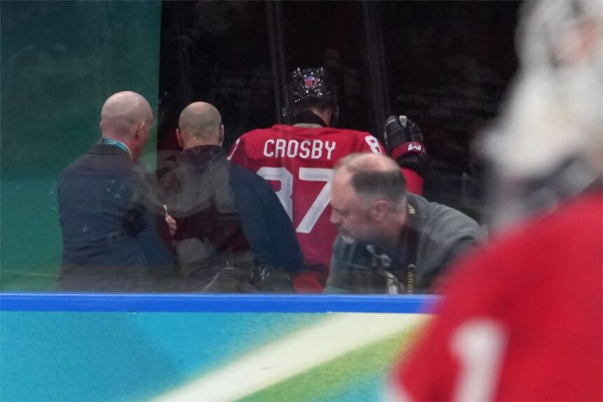 Canada's Sidney Crosby (87) is helped as he leaves the bench after being checked against the boards during the second period of a men's ice hockey quarterfinal game between Canada and Czechia at the 2026 Winter Olympics, in Milan, Italy, Wednesday, Feb. 18, 2026. (AP Photo/Carolyn Kaster)
