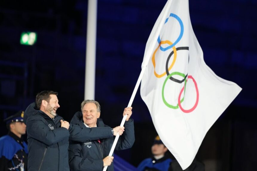 President of the Provence-Alpes-Cote d'Azur Region Renaud Muselier, right, and President of the Auvergne-Rhone-Alpes Region Fabrice Pannekoucke wave the Olympic flag during the closing ceremony of the 2026 Winter Olympics, in Verona, Italy, Sunday, Feb. 22, 2026. (AP Photo/Natacha Pisarenko)