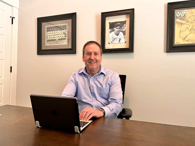 Erik Simpson in his den sitting below a photo of his grandfather. | Rett Nelson, EastIdahoNews.com