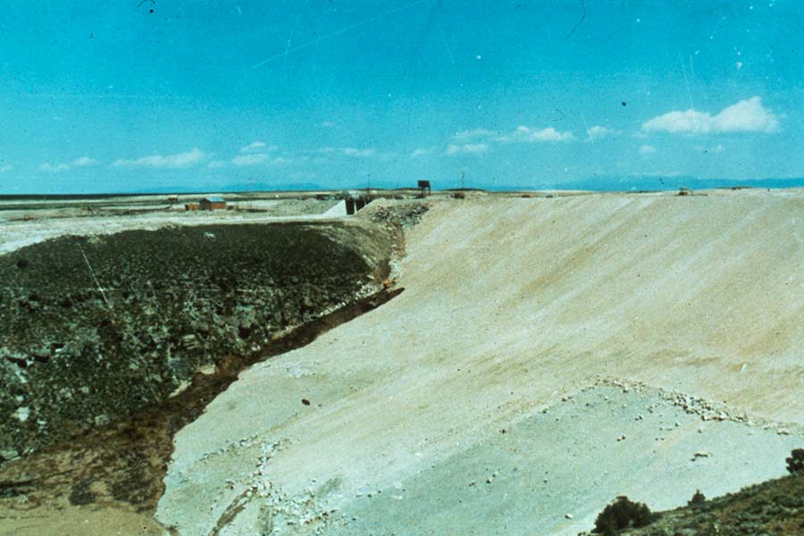 A photo of the Teton Dam the morning of the break. The dark streak along the right side of the dam (the left side of the photo) is water springing from the leak. June 5th, 1976. | Courtesy BYU-Idaho