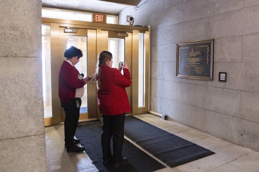 Capitol tour guides take photos of a plaque honoring police service on Jan. 6, 2021 at the Capitol, Saturday, March 7, 2026, in Washington.