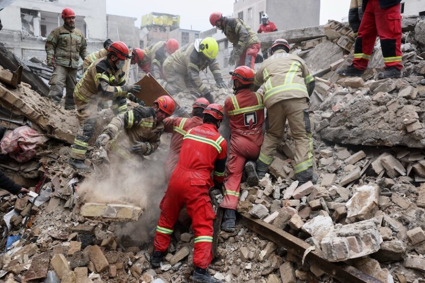 Rescue workers search for survivors in the rubble after a strike in southern Tehran, Iran, Friday, March 13, 2026