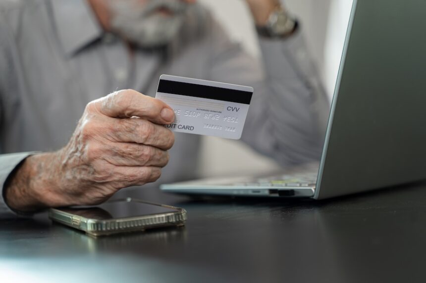 Mature man hold credit card make online payment or purchase from home,E-commerce retail services client.