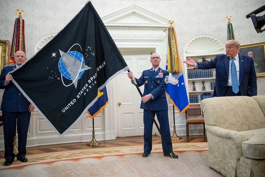 FILE - Gen. John "Jay" Raymond, Commander U.S. Space Command, left, and Chief Master Sgt. Roger Towberman, center, hold the Space Force Flag as President Donald Trump gestures to it during the presentation of the in the Oval Office of the White House in Washington on May 15, 2020.