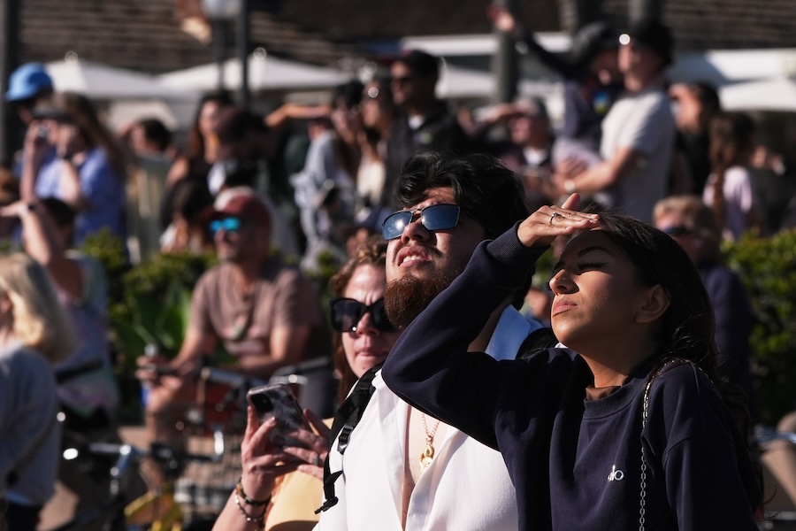People wait for a glimpse of the return of NASA's Artemis II Friday, April 10, 2026, along the beach in Coronado, Calif.