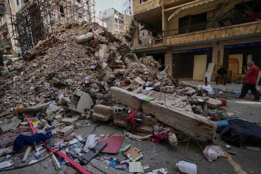 Residents stand next to the rubble of a destroyed building that was hit a week ago in an Israeli airstrike in central Beirut, Lebanon, Thursday, April 16, 2026.