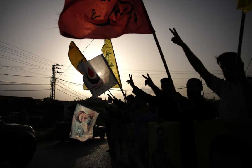 People wave Hezbollah flags and an image of late Hezbollah leader Hassan Nasrallah, in Zefta, southern Lebanon, Friday, April 17, 2026, as displaced residents drive back to their villages following a ceasefire between Israel and Hezbollah.