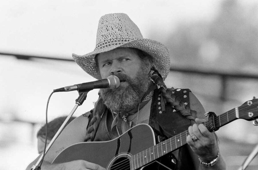 FILE - David Allan Coe, sporting Willie Nelson braids, performs at the Willie Nelson July 4th Picnic, on July 4, 1983 at Atlanta International Raceway in Hampton, Ga.
