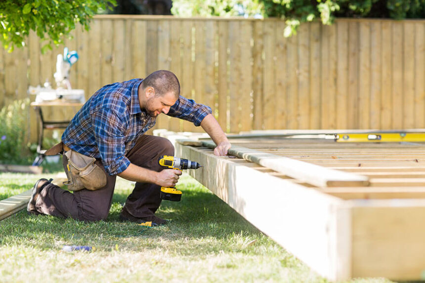 man works on backyard deck