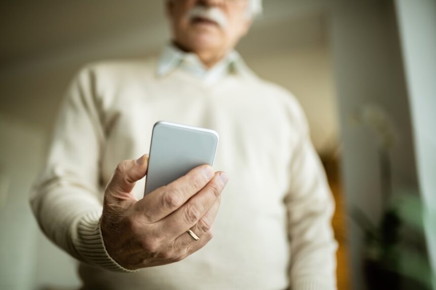 Close-up of mature man using smart phone at home.