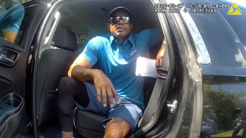 In this image from police body camera video released by the Martin County, Fla., Sheriff's Office, golfer Tiger Woods sits in an unmarked police vehicle as he speaks with law enforcement personnel following a car crash in Jupiter Island, Fla., Friday, March 27, 2026. (Martin County Sheriff's Office via AP)