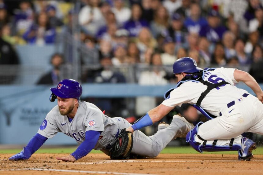 Chicago Cubs' Michael Busch, left, is tagged out by Los Angeles Dodgers catcher Will Smith, right, while attempting to score off a single hit by Alex Bregman during the fourth inning of a baseball game Friday, April 24, 2026, in Los Angeles. (AP Photo/Ryan Sun)