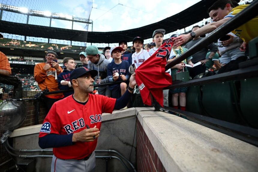 Boston Red Sox manager Alex Cora, foreground, gives autographs to fans before a baseball game against the Baltimore Orioles, Friday, April 24, 2026, in Baltimore. (AP Photo/Nick Wass)