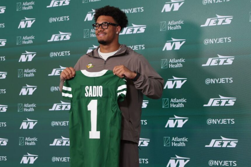 New York Jets first round draft pick Kenyon Sadiq holds up his jersey during an introductory press conference at the NFL team's training facility, Saturday, April 25, 2026, in Florham Park, N.J. (AP Photo/Heather Khalifa)