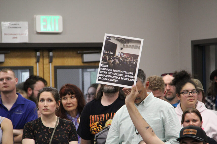 An audience member holds up a news article during the meeting.