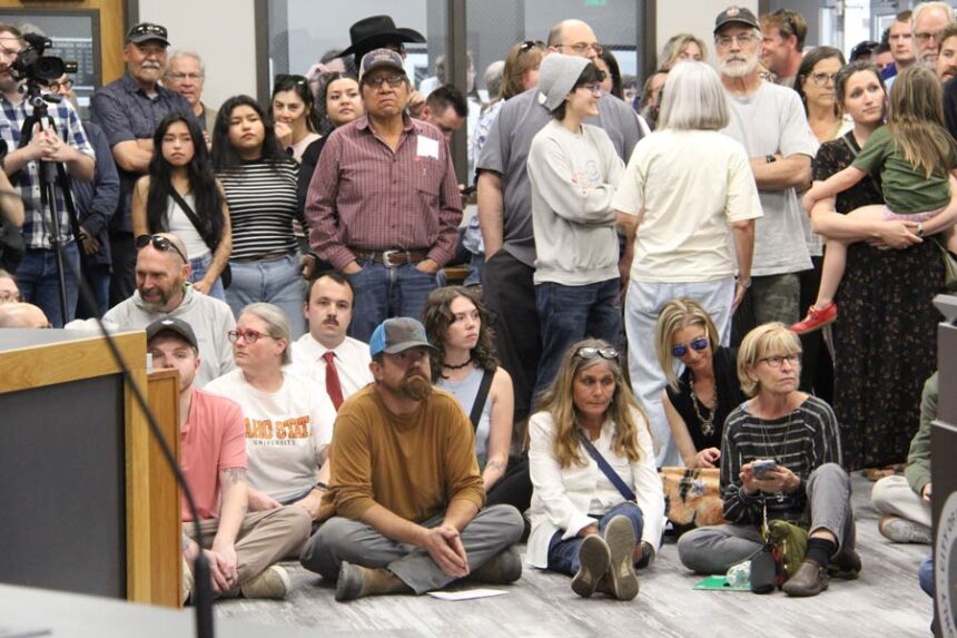 Some sit as they wait for the public hearing to begin.