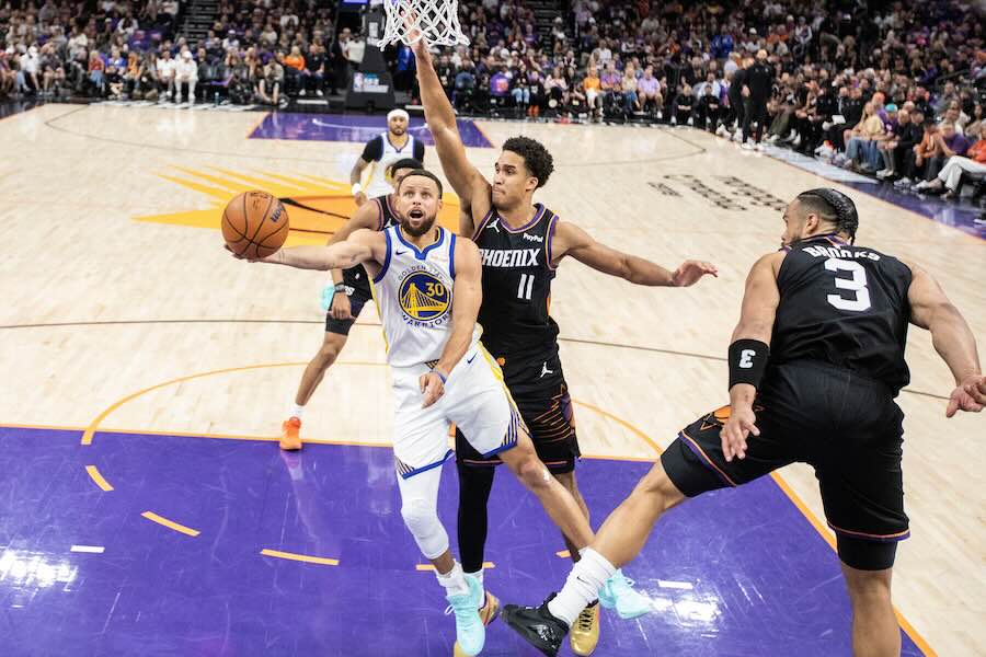 Golden State Warriors guard Stephen Curry (30) drives for a layup as Phoenix Suns forward Oso Ighodaro (11) defends during the first half of their NBA play-in tournament game at Mortgage Matchup Center in Phoenix, Ariz., Friday, April 17, 2026.