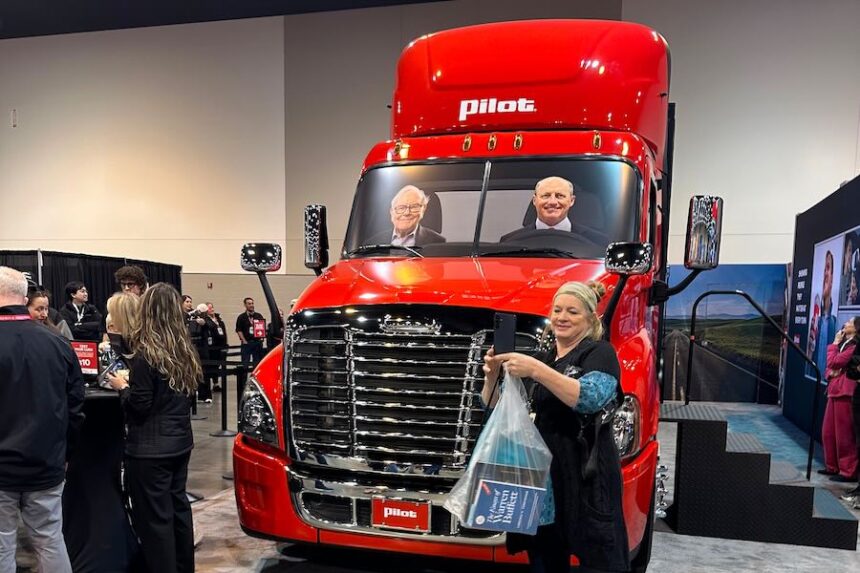 A Berkshire Hathaway shareholder takes a selfie in front of a Pilot truck stops semi truck with pictures of Berkshire's top two executives behind the wheel: new CEO Greg Abel and Chairman Warren Buffett on Friday, May 1, 2026 in Omaha, Neb.