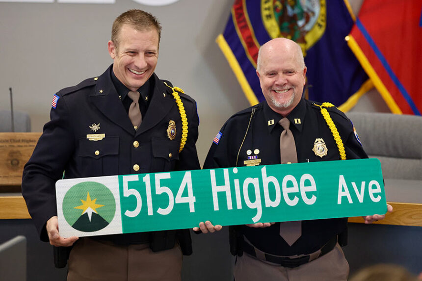 Chief Roger Schei (left) stands with Captain Chad Higbee holding a custom made street sign.