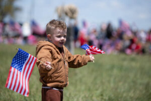 A child waves flags outside of American Heritage Charter School during a celebration for the 250th anniversary of the United States. | Cody Roberts, EastIdahoNews.com