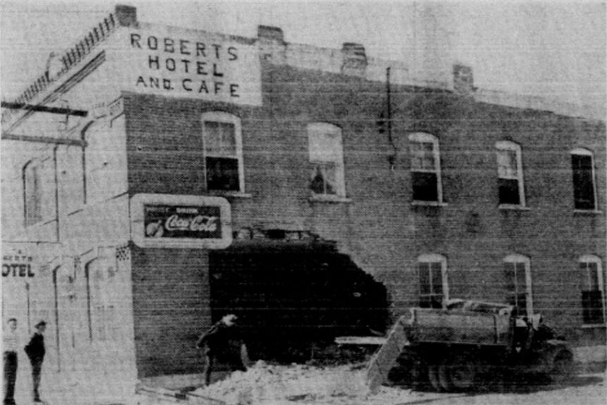 The Roberts Hotel lobby was dusted free of sand and brick Thursday after a truck loaded with sand crashed through the brick wall into the lobby. The lobby, however, had more fresh air than the proprietors would like with the gaping 12 by 15 foot hole left by the crash. Driver of the truck, Thomas Jack, of Roberts, who escaped without injury, told state patrolmen investigating the accident that he was forced to swerve when a car in front of him turned off the road suddenly. Jack said the wheels locked and he was forced to crash into the side of the hotel. Fortunately no one was in the lobby at the time of the accident. The truck, its cab flattened, is shown at right after being hauled from the lobby. Caption dated May 25, 1950.
