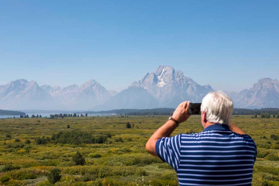 Steve Carringer of Tennessee takes a photo of the mountains at Jackson Lake Lodge in Grand Teton National Park near Moran, on Aug. 22, 2024. (AP Photo/Amber Baesler)