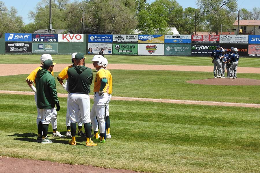 The Bonneville Bees meet near their dugout while the Twin Falls Bruins meet on the mound during the third inning.
