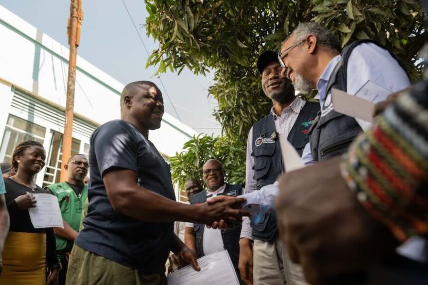 Director General of the World Health Organisation (WHO), Tedros Adhanom Ghebreyesus, right, shakes hands with Ezo Etienne, a health worker who recovered from Ebola in Bunia, Congo, Sunday, May 31, 2026.