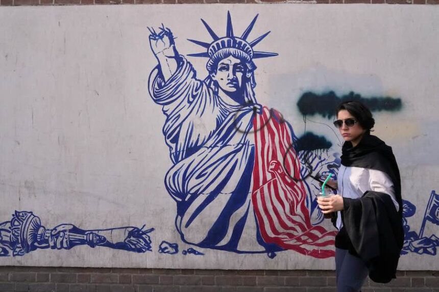A woman walks past an anti-American mural on the wall of the former U.S. Embassy, now a museum, in Tehran, Iran, Friday, June 12, 2026.