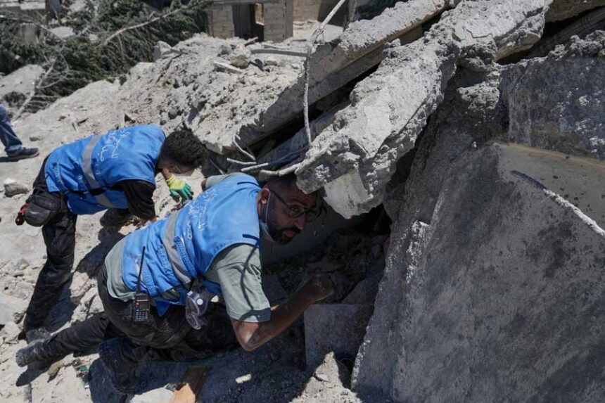 Rescue workers search for victims under the rubble of a destroyed building that was hit in an Israeli airstrike in Qannarit village, southern Lebanon, Saturday, June 20, 2026.