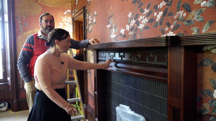 Chelom Leavitt gestures to a fireplace mantel while giving a KSL news crew a tour of her Scottish mansion in 2026. Her husband, David Leavitt, stands behind her.