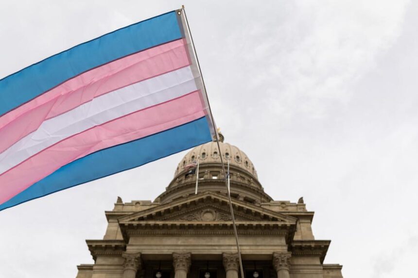 At a Transgender Day of Visibility rally on March 31, 2026, in front of the Idaho State Capitol in Boise, a person holds a transgender pride flag in front of the state Capitol. (Photo by Kyle Pfannenstiel/Idaho Capital Sun)