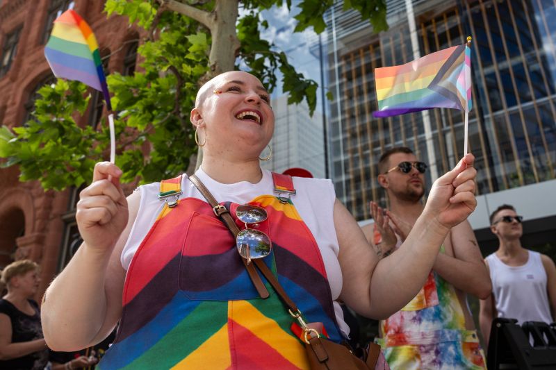 Cassidy Hackley smiles while waving pride flags during the Utah Pride Parade in downtown Salt Lake City on Sunday.  - Rio Giancarlo, Deseret News