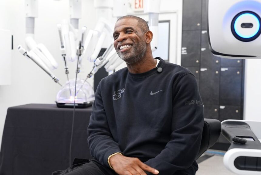 Colorado head football coach Deion Sanders talks about working the Da Vinci robotic surgical machine used to remove his cancerous bladder last year during a demonstration of the device Tuesday, June 23, 2026, in Boulder, Colo. (AP Photo/David Zalubowski)