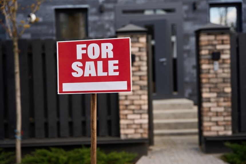 Sale notice installed on the lawn near the entrance to the house.