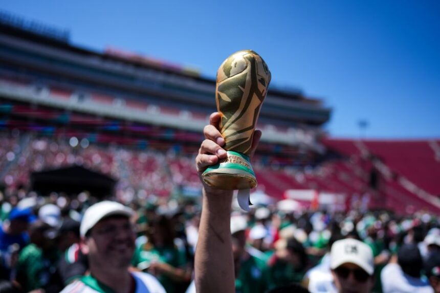 A fan holds up a replica of the World Cup trophy at a fan festival at the Los Angeles Memorial Coliseum in Los Angeles, Thursday, June 11, 2026, during a live broadcast of the World Cup soccer match between Mexico and South Africa. (AP Photo/Jae C. Hong)