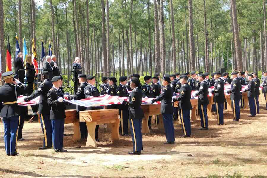 Military personnel fold flags for the remains of 12 Continental soldiers killed at the Battle of Camden, S.C., during a memorial ceremony on April 22, 2023.