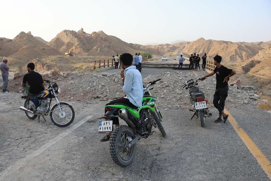 People stand on a bridge destroyed after a strike in Hormozgan province, southern Iran, Saturday, July 18, 2026.